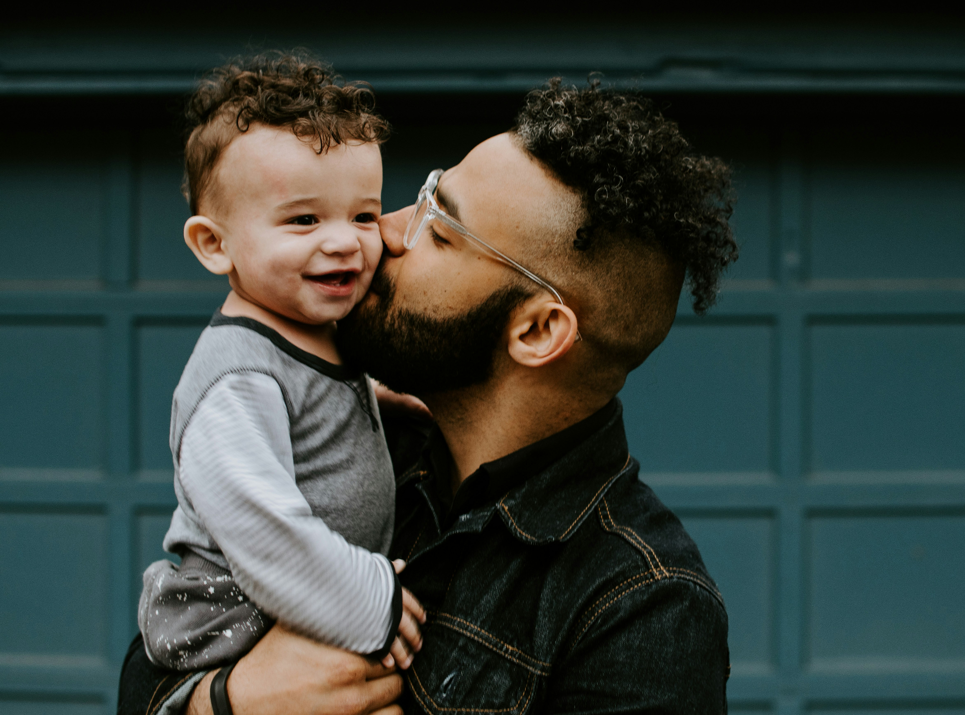 Father kissing his smiling young son on the cheek