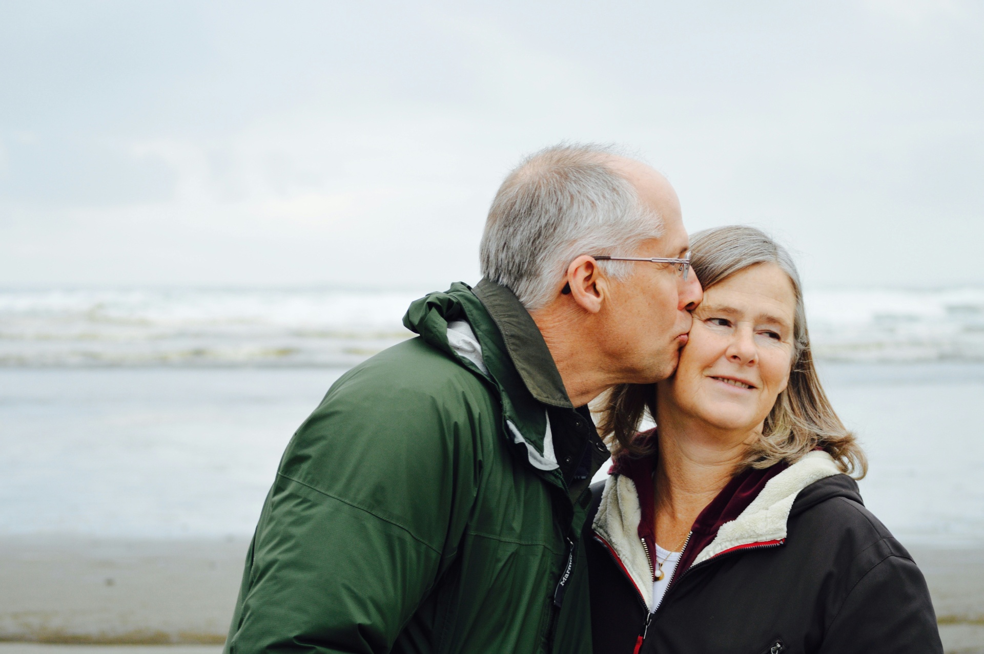 An older couple sharing a tender moment on a windswept beach