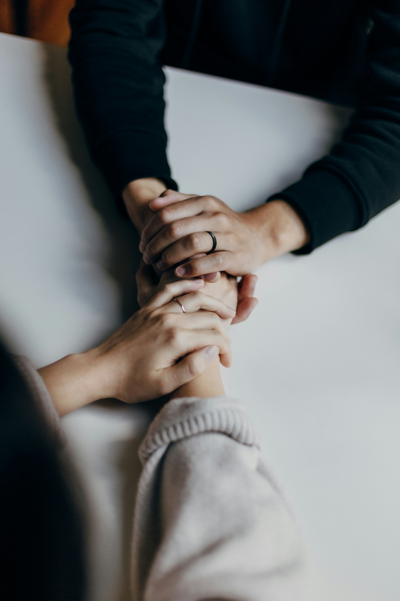 Hands clasped in comfort across a table